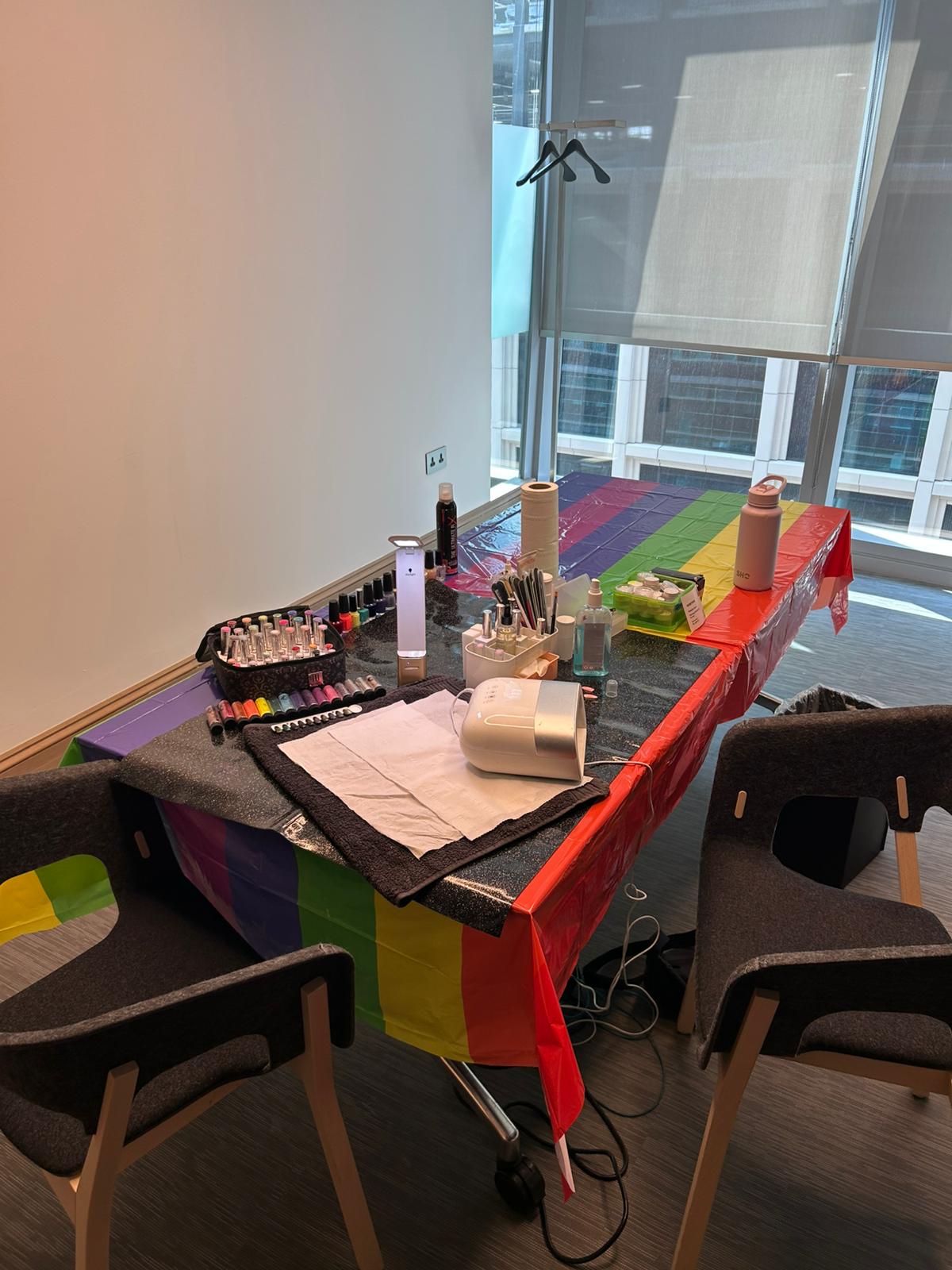 Mobile manicure station set up for a Pride office event in St James’s Park, London, featuring rainbow tablecloth, gel polish selection, and nail art tool