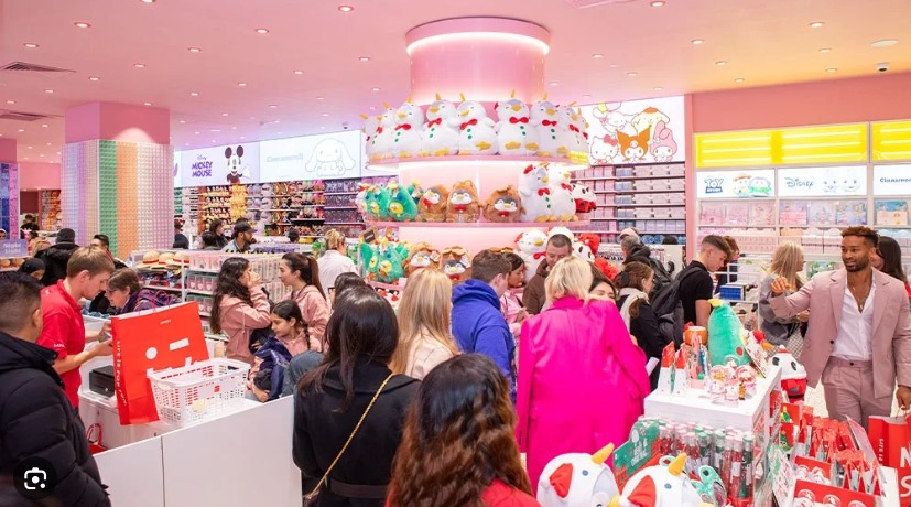 A lively interior of a retail store filled with colorful merchandise, including plush toys and beauty products, with a crowd of shoppers interacting amongst displays.