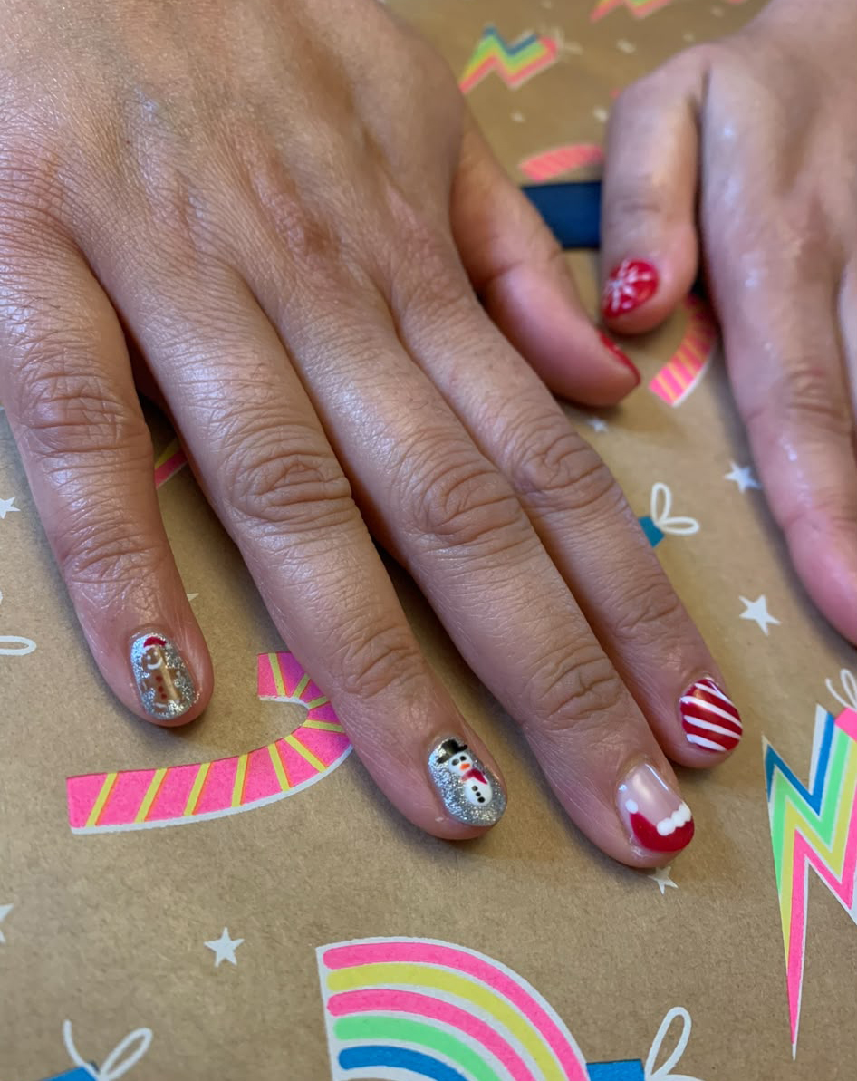 Christmas is coming Close-up of festive manicure with red, silver, glitter, snowman, and candy-cane nail designs