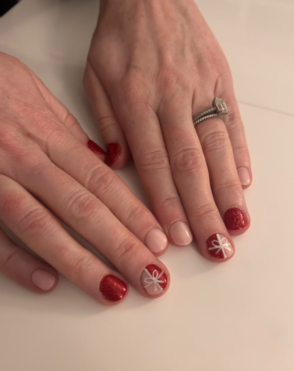 Christmas is coming! Hands with red glitter and nude holiday nails featuring white bow designs and a ring