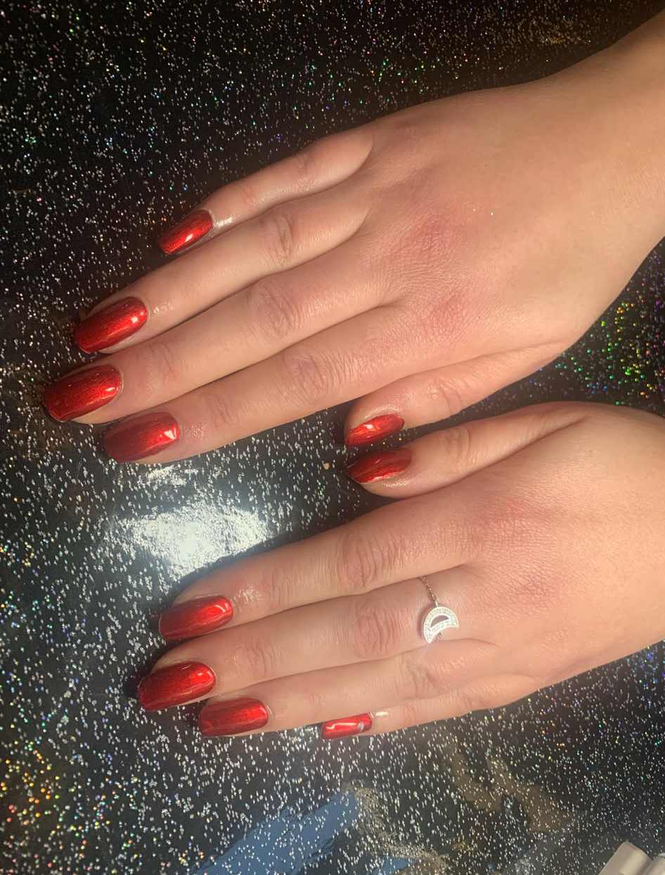 Christmas is coming Hands with glossy red manicured nails resting on a glittery black surface