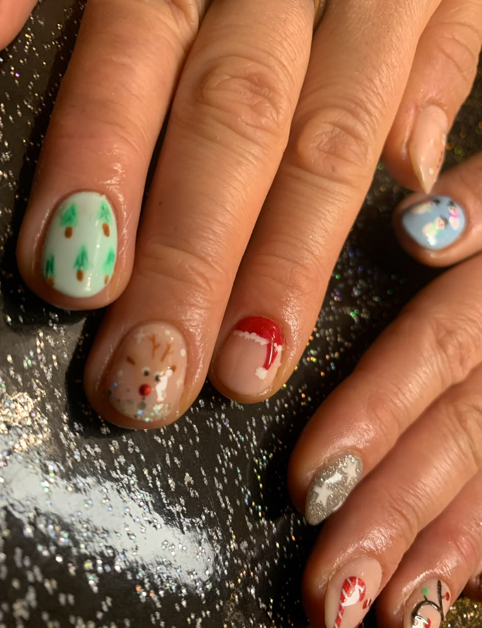 Christmas is coming! Close-up of festive Christmas-themed nail art with trees, reindeer, snowflakes, and glitter