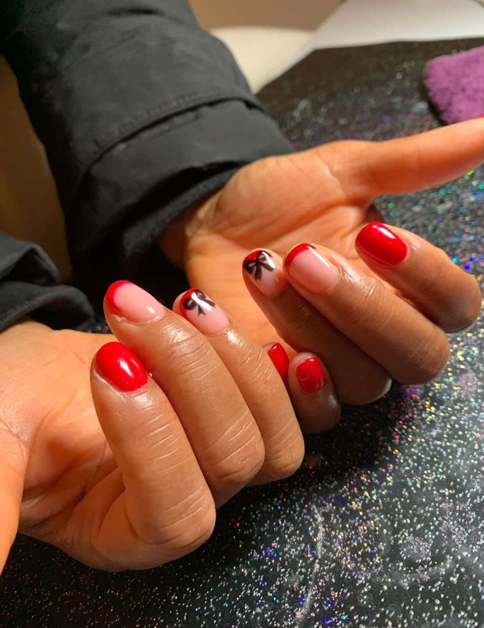 Christmas is coming! Close-up of hands with red and pink French-tip nails and butterfly accents